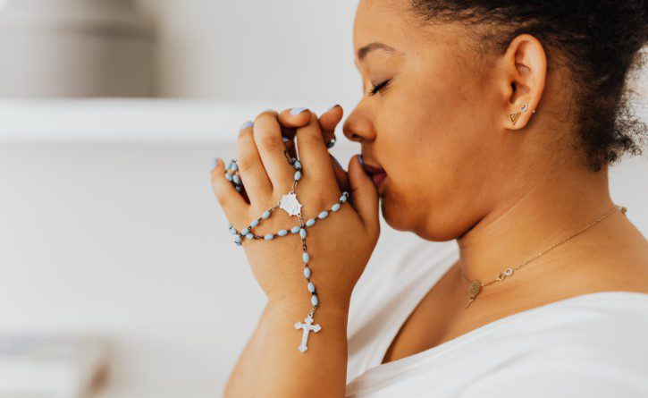 A woman praying with her hands in front of her face.